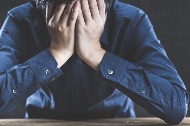 顔を覆って悩む男性